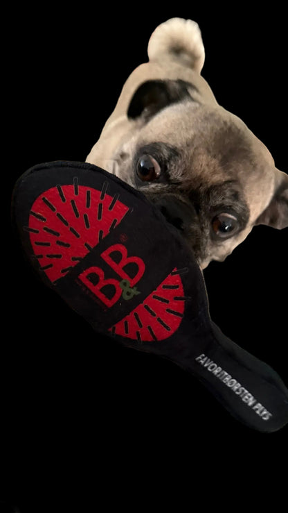 Enthusiastic pug holding a plush squeaky toy inspired by the B&B Favorite Brush