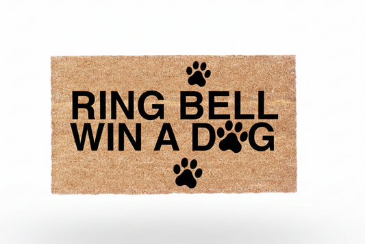 Ring Bell Win a Dog coir doormat with black lettering and paw print design on natural coconut fiber