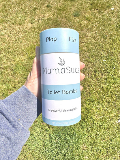 Hand holding MamaSuds Toilet Bombs canister outdoors.