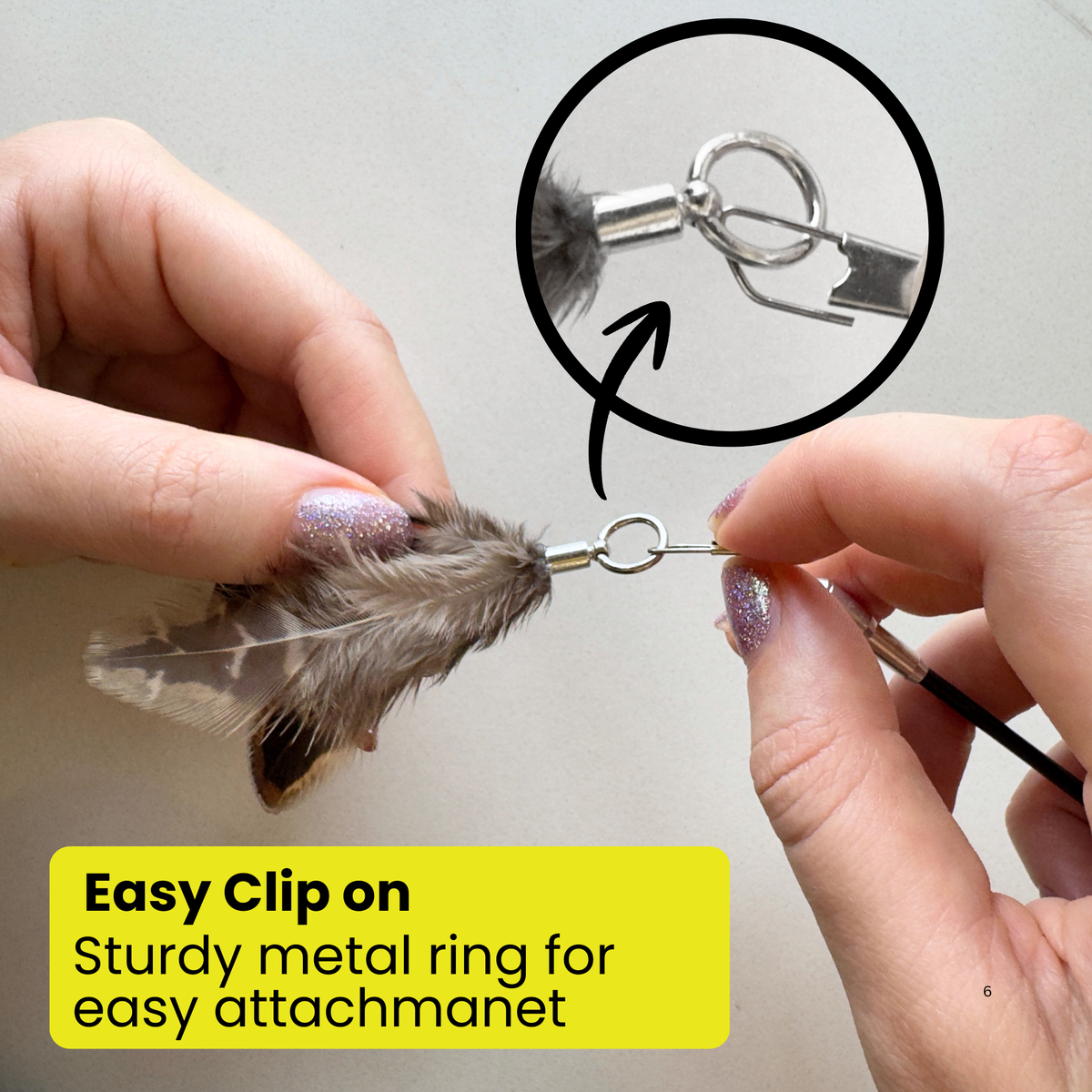 Close-up of Repounce natural feather toy attachment being clipped onto a cat wand with a sturdy metal ring
