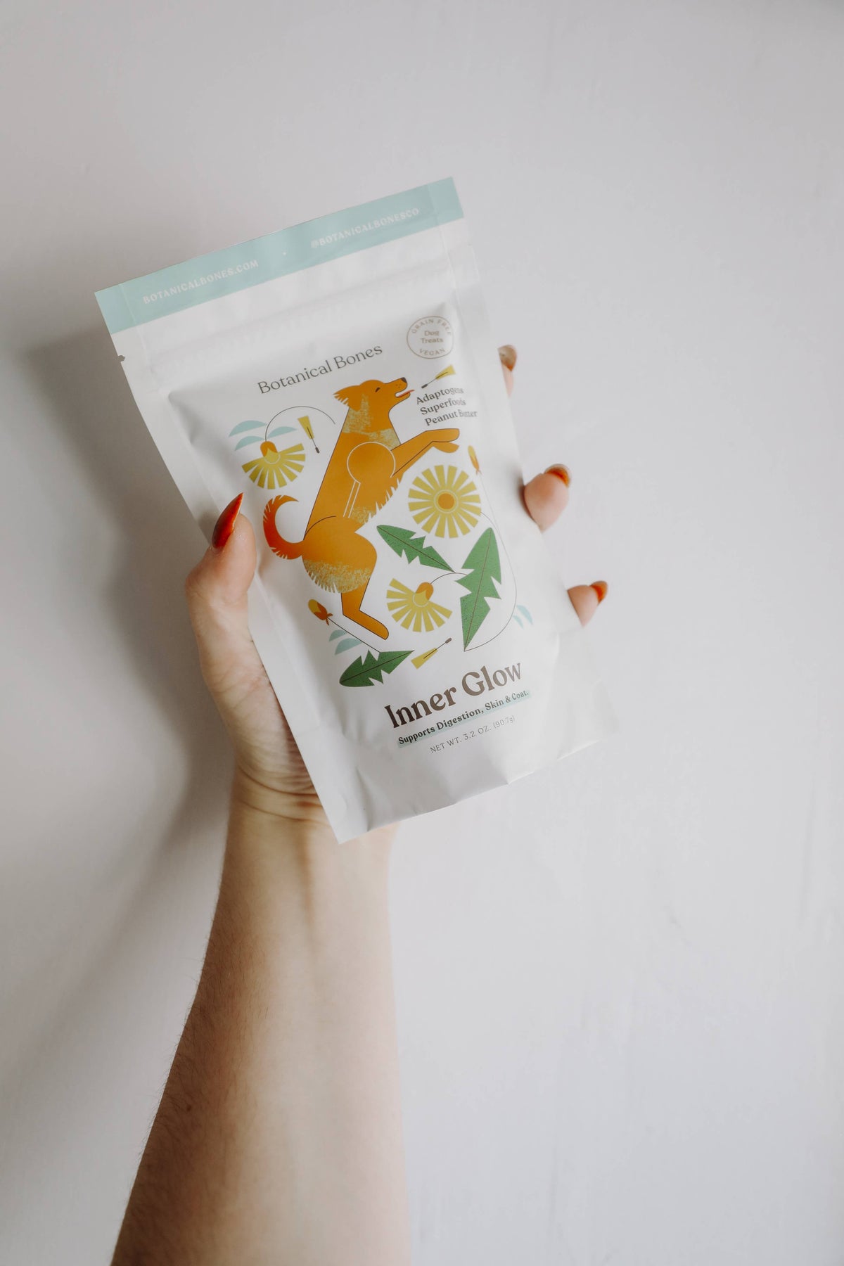 Hand holding Botanical Bones Inner Glow organic dog treats package