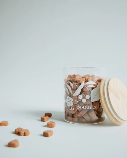 Love Bites organic dog treats spilled from a glass jar.